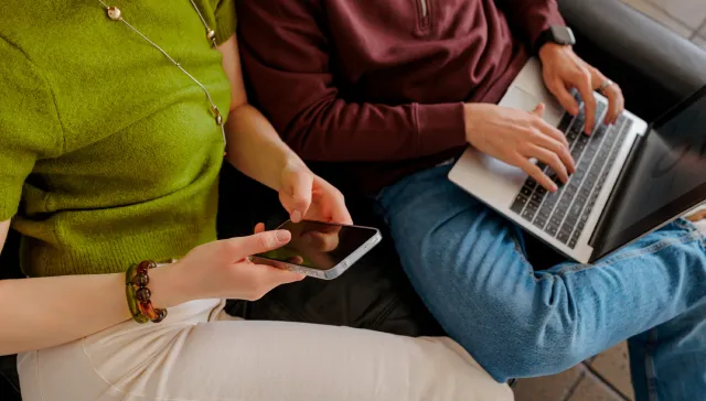 Un couple qui tape sur un ordinateur portable et un téléphone portable.