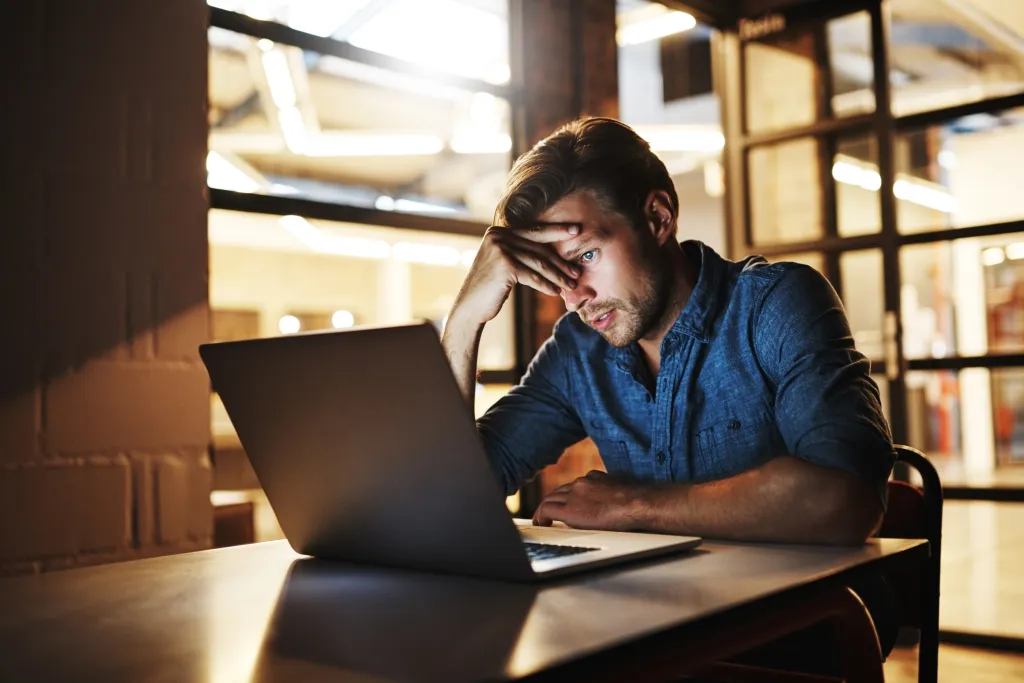 Un homme d’affaires nerveux regarde son ordinateur portable dans un bureau