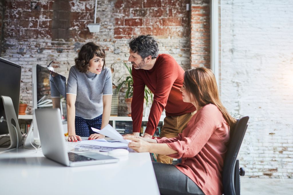 Un homme et deux femmes professionnelles discutant d'idées à une table de travail
