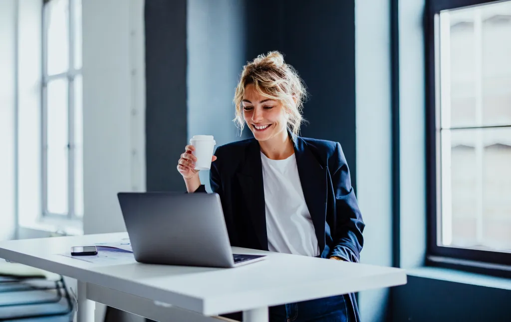 Image d’une femme savourant un café tout en travaillant avec son ordinateur portable