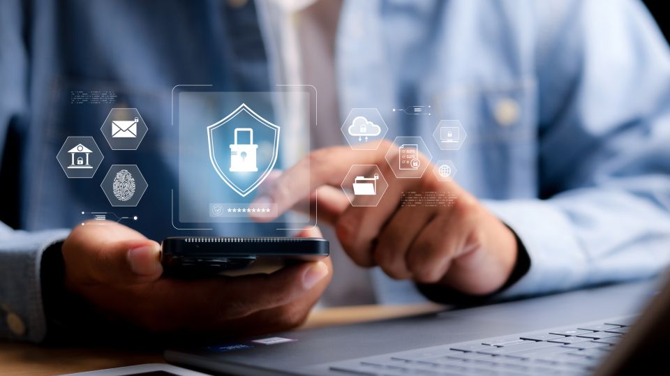 Personne tenant un smartphone avec des icônes de sécurité numérique
