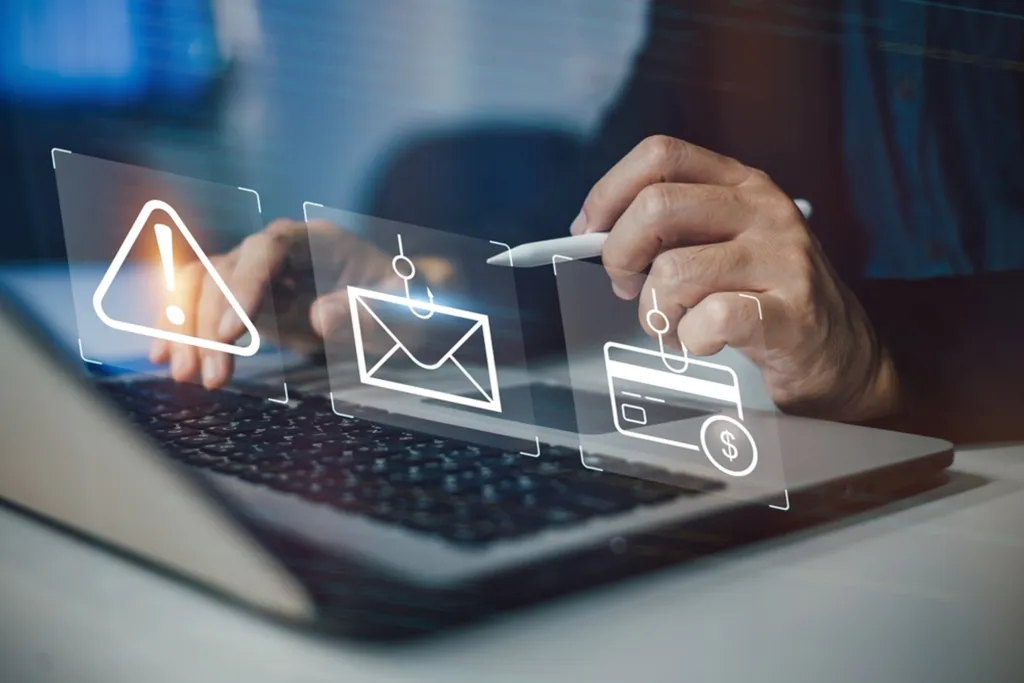 Personne pointant vers trois icônes de fraude sur un écran d’ordinateur.