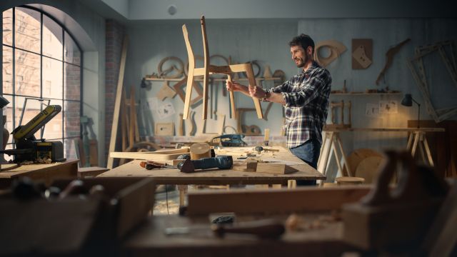 Un artisan inspecte une chaise en bois faite à la main en atelier
