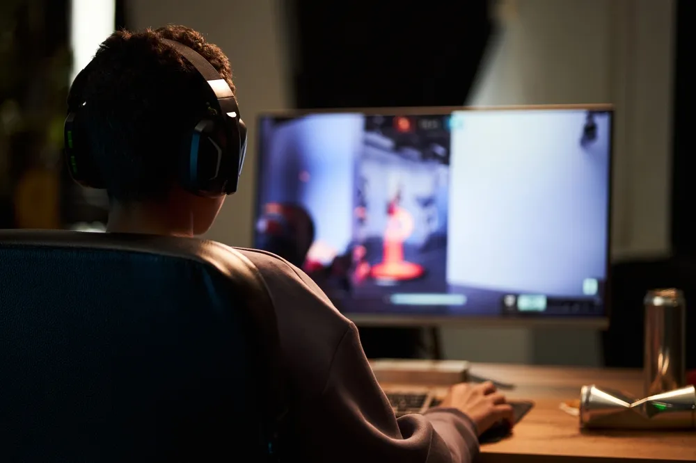 Teenage boy participating in an online game while sitting at his desk.