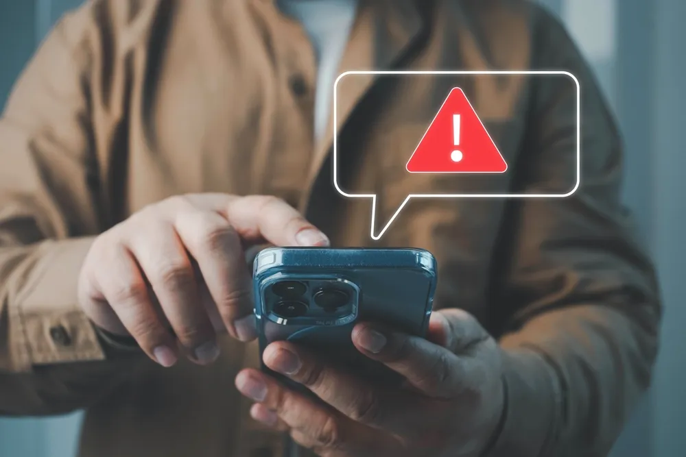 Un homme tenant un téléphone tout en étant informé d’une arnaque.