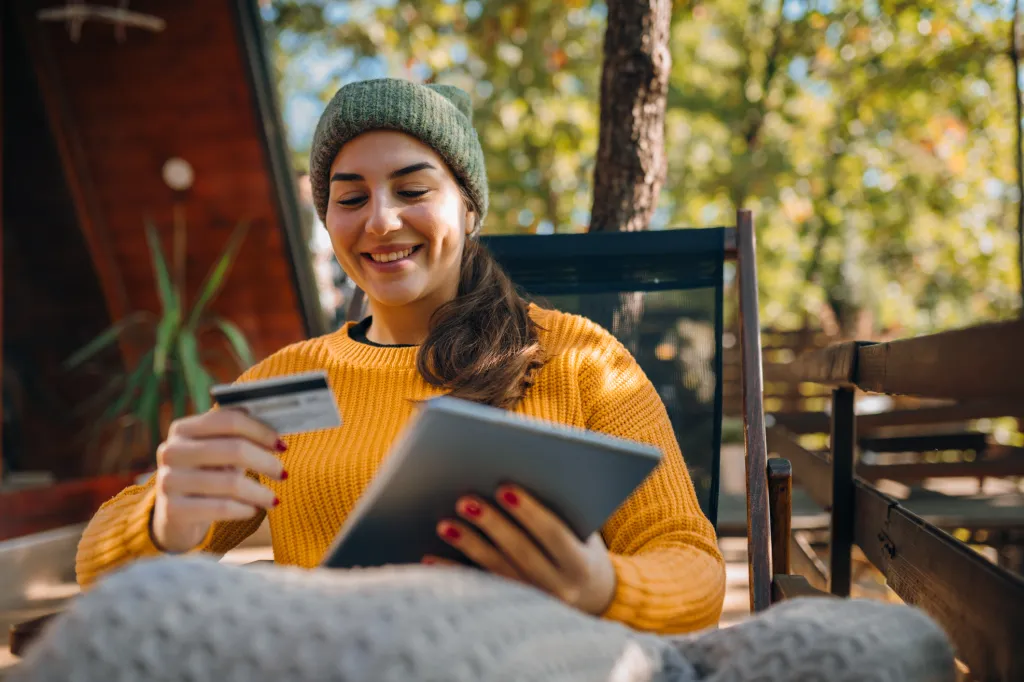 Une jeune femme utilise une tablette numérique pour faire des achats en ligne par une journée d’automne ensoleillée